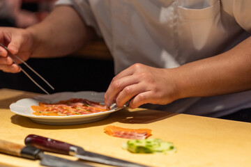 Chef preparing sushi with fresh ingredients on wooden countertop