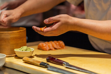 Sushi chef preparing fresh sushi with vibrant ingredients on wooden table