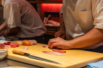 Skilled chef preparing sushi with fresh ingredients on wooden cutting board