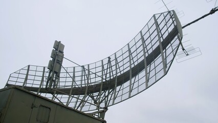 industrial radar system scanning sky above, large antenna on platform monitors drones and airplanes