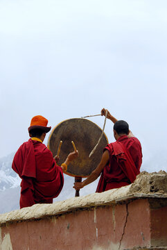 Tibetan Buddhist Lama Performing Ritual Drum Ceremony on Monastery Rooftop in Zanskar Valley, Ladakh, India