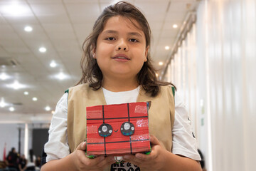 Portrait of a Latino boy smiling and looking at the camera with a robot in his hands in an auditorium in Neiva, Huila, Colombia. Concept of science and robotics