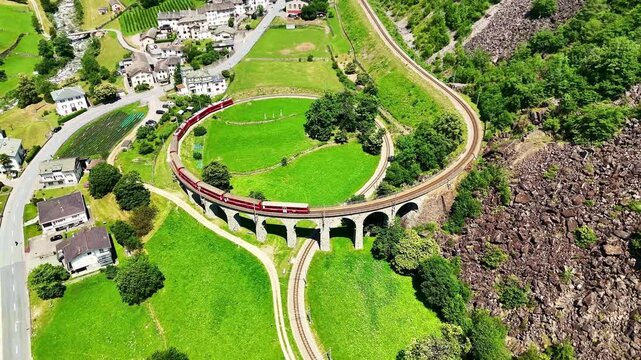 Drone Switzerland 4k.  train on way to St. Moritz. Brusio spiral viaduct, stone spiral railway viaduct on the Bernina Railway. Swiss Alps in summer. 
