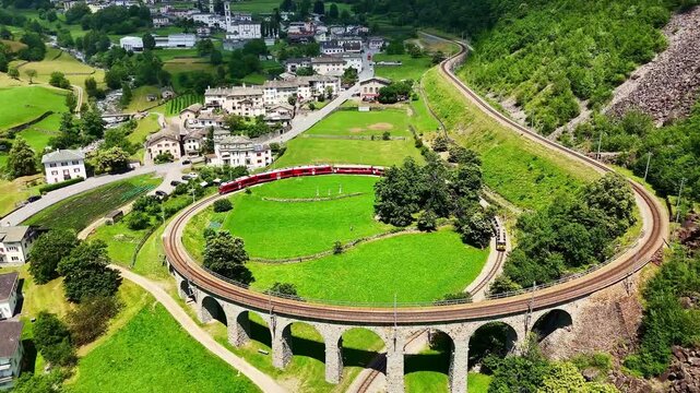 Drone Switzerland 4k.  train on way to St. Moritz. Brusio spiral viaduct, stone spiral railway viaduct on the Bernina Railway. Swiss Alps in summer. 
