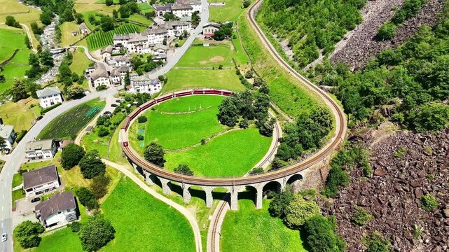 Drone Switzerland 4k.  train on way to St. Moritz. Brusio spiral viaduct, stone spiral railway viaduct on the Bernina Railway. Swiss Alps in summer. 
