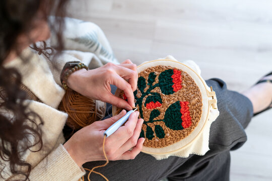 woman knitting wool. Creative embroidery session in a cozy indoor space with floral design being crafted on fabric