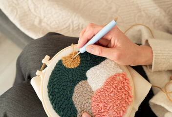 Detailed hand crafting of a colorful textile art piece in a cozy indoor setting during the afternoon © Natali