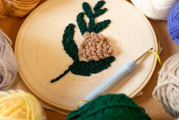 Crafting a detailed embroidery design with colorful yarns and a crochet hook on a workbench