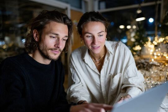 A young couple sits together engaged with a laptop, sharing ideas in an intimate atmosphere full of creativity and warmth, capturing modern collaboration in a cozy setting.