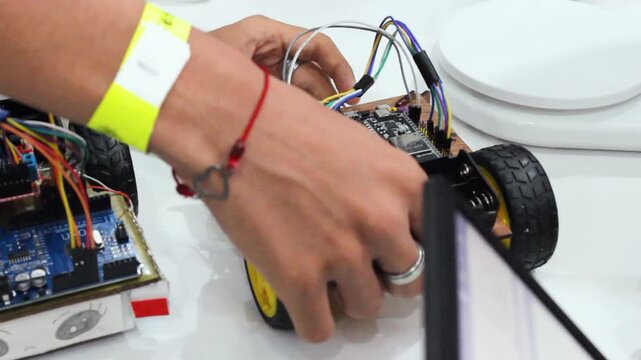 Hands of an unrecognizable person assembling a small robot on a scale at a science and technology fair in Neiva, Huila, Colombia. Concept of innovation and handmade