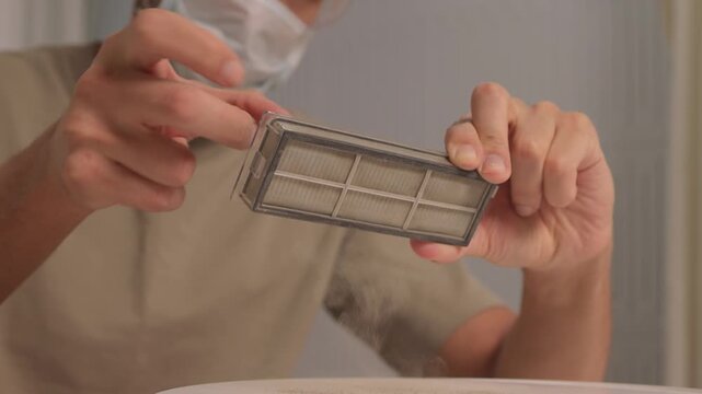 Hands check filter, Demonstration of cleaning vacuum filter in home kitchen environment, Closeup of person inspecting and cleaning dusty vacuum filter in domestic setting