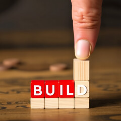 Hand placing a red block labeled 'BUILD' into a wooden structure, symbolizing business strategy, foundation, and development.