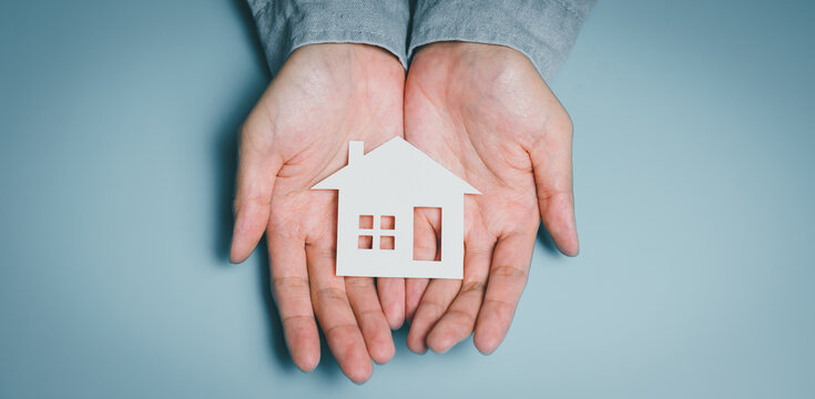 Hands holding white paper house, family home security, mental stability, financial planning, stress relief, life balance, community support, housing care responsibility, safety concept