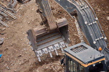 Excavator bucket digging into soil during construction work, showing power, precision, and heavy machinery in action.