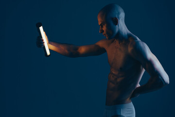 Strong man holding a flashlight, showcasing determination in a dark environment. The dim lighting...