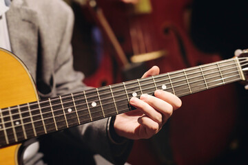 Obraz premium Concert view of acoustic electric guitar player with vocalist and rock band performing in a club, male musician guitarist on stage with audience in a crowded concert club hall arena, hands on guitar