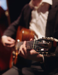 Concert view of acoustic electric guitar player with vocalist and rock band performing in a club,...
