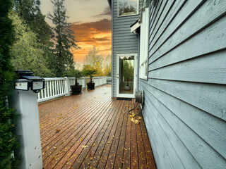 wood deck during late autumn fall season with lots of leaves on patio to be cleaned after the rain storm