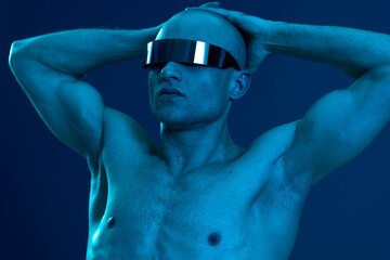 Stylish man with futuristic glasses posing dramatically, showcasing a striking blue light...