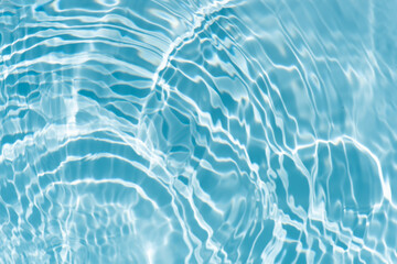 Blue water with ripples on the surface. Defocus blurred transparent blue colored clear calm water surface texture with splashes and bubbles. Water waves with shining pattern texture background.
