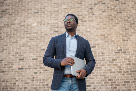 Young black man holding laptop looking confident and aspiring