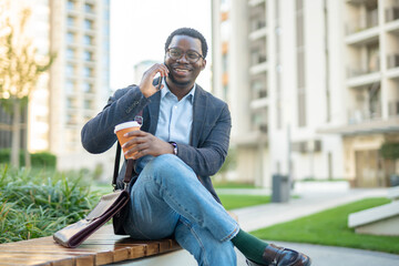 Obraz premium Young black man talking on smartphone drinking coffee