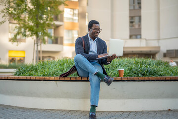 African american man using laptop outdoors working remotely