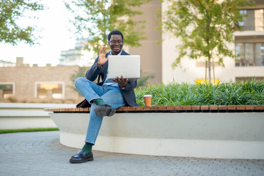 African american man waving during video call on laptop