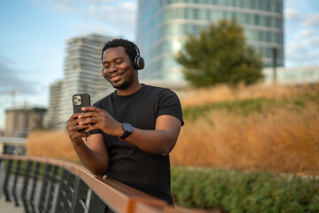 Happy black man enjoying music and digital content outdoors