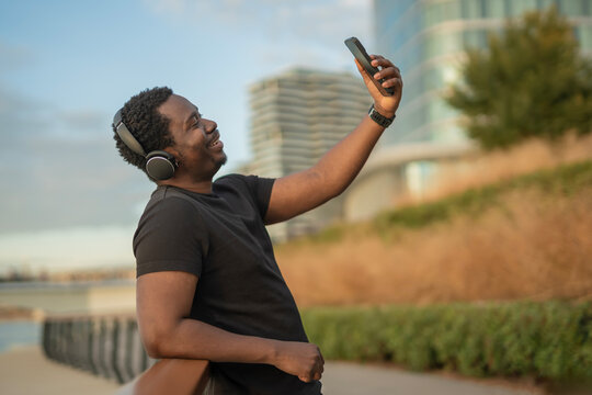Smiling black man taking selfie with smartphone and headphones