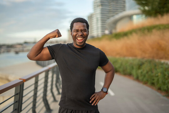Happy black man flexing arm showing muscle