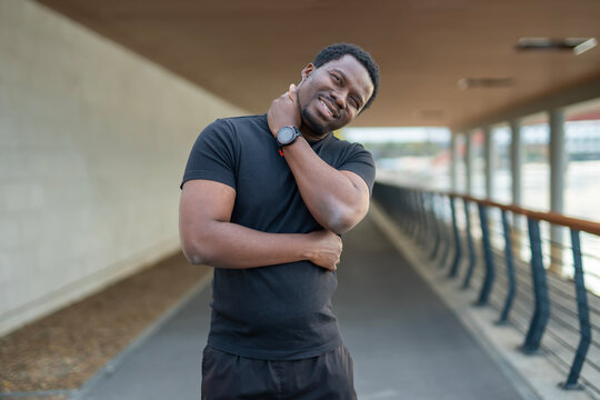 Young black man stretching neck smiling outdoors