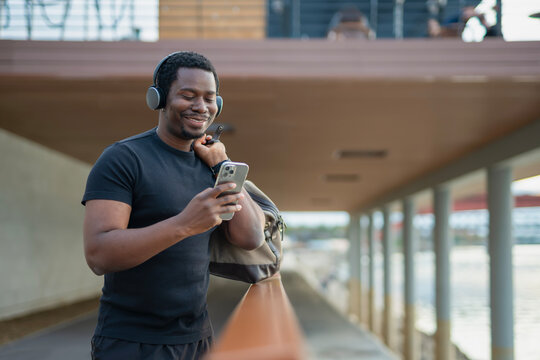 African american man smiling using smartphone listening music