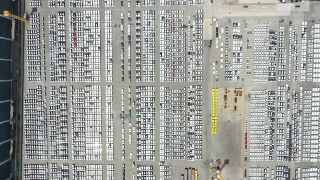 Cars export terminal in export and import business and logistics. Shipping cargo to harbor. Aerial view of a large number of new cars lined up outside an automobile factory ready to ship over sea.