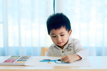 Cute boy learning to draw and color