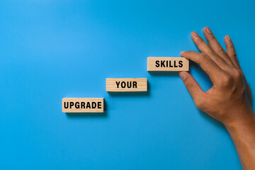 male hand put wooden blocks with upgrade your skills words isolated on blue background