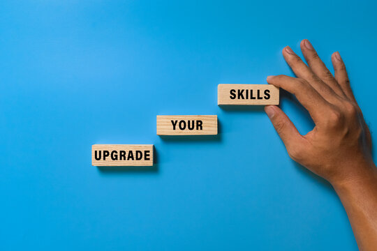male hand put wooden blocks with upgrade your skills words isolated on blue background