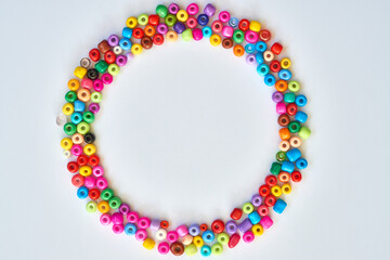 Fototapeta premium Colorful craft beads arranged in a circular pattern on a white background for creative projects