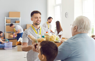 Volunteering people, food bank box giving help to old senior man, male volunteer working in charitable meal foundation making donation, charity separating basic need provisions, free meal help care
