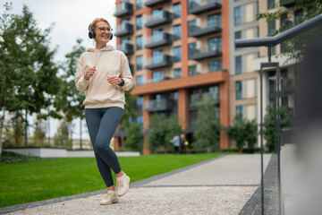 Happy mature woman exercising outdoors listening to music