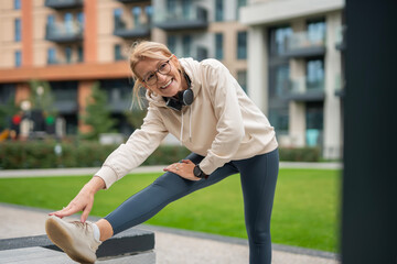 Fototapeta premium Mature woman stretching leg enjoying outdoor exercise