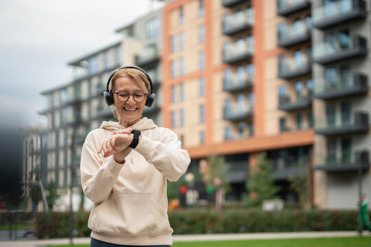 Mature woman checking smartwatch while exercising outdoors