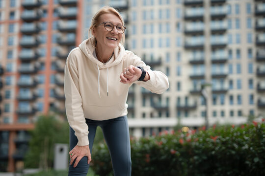 Happy woman checking smartwatch during urban workout break
