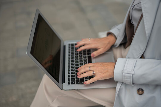 Person typing on laptop keyboard working remotely outdoors