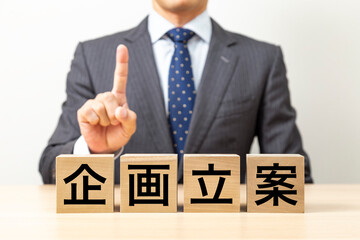 Obraz premium 「企画立案」と書かれたブロックとビジネスマン