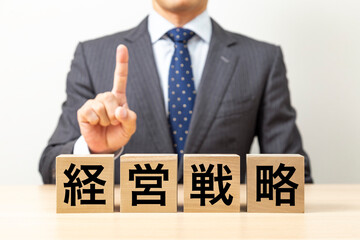 「経営戦略」と書かれたブロックとビジネスマン