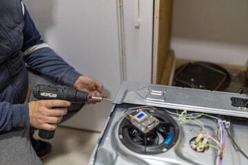 Handyman using power drill fixing kitchen appliance