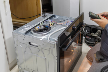 Technician checking electric wiring of kitchen oven