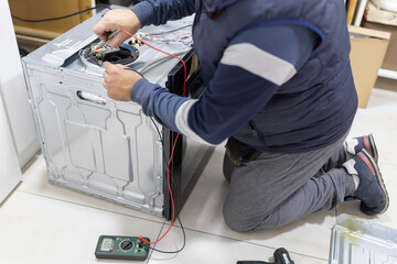 Technician checking household appliance wiring with a multimeter