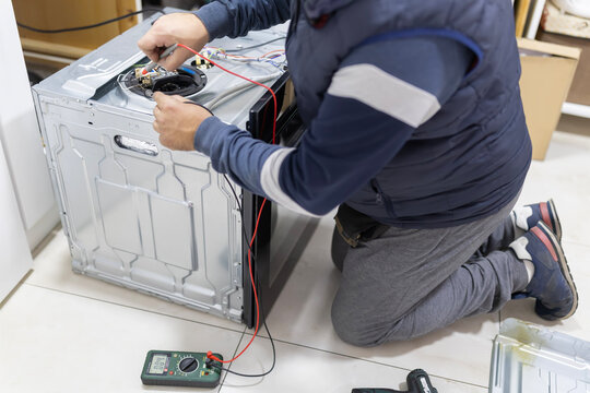 Technician checking household appliance wiring with a multimeter